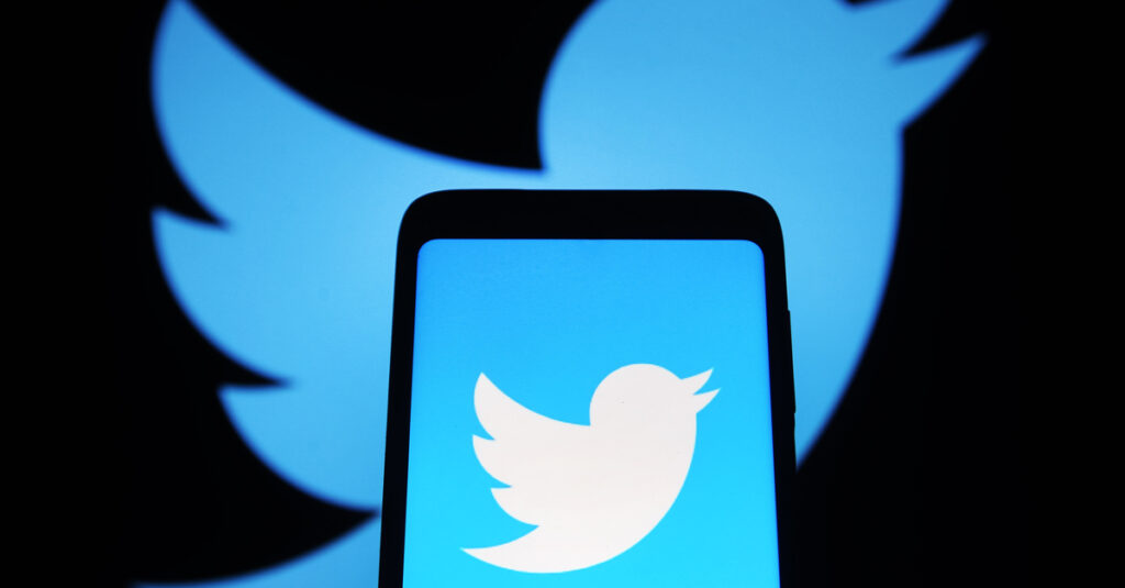 Twitter logo in background with twitter logo on phone in foreground