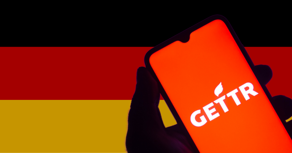 Hand using mobile with Gettr logo, with German flag in background