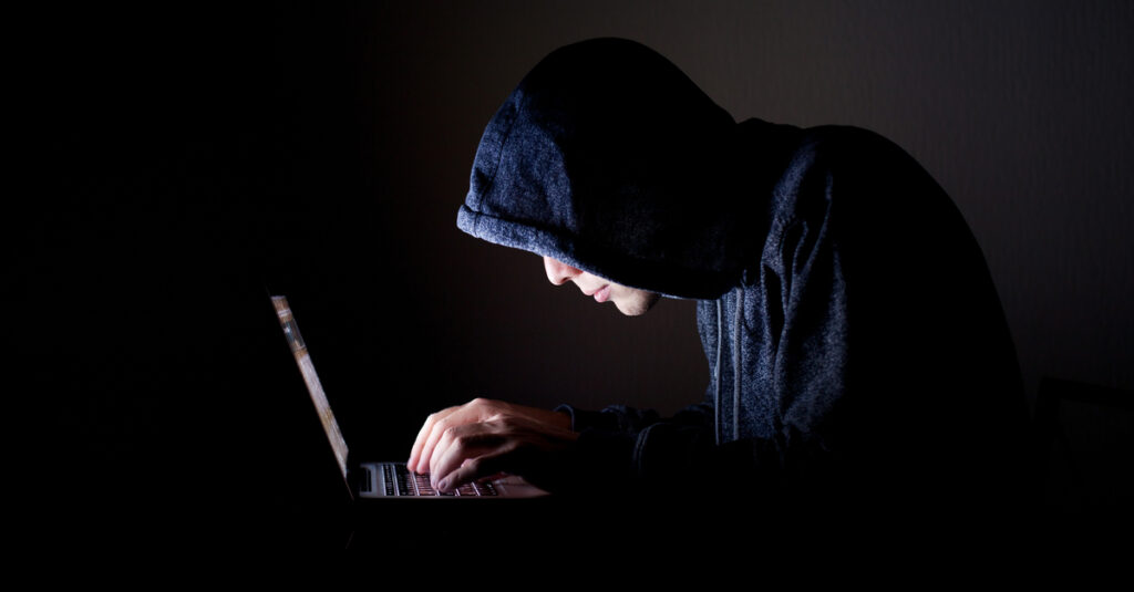 young man in hoodie using laptop